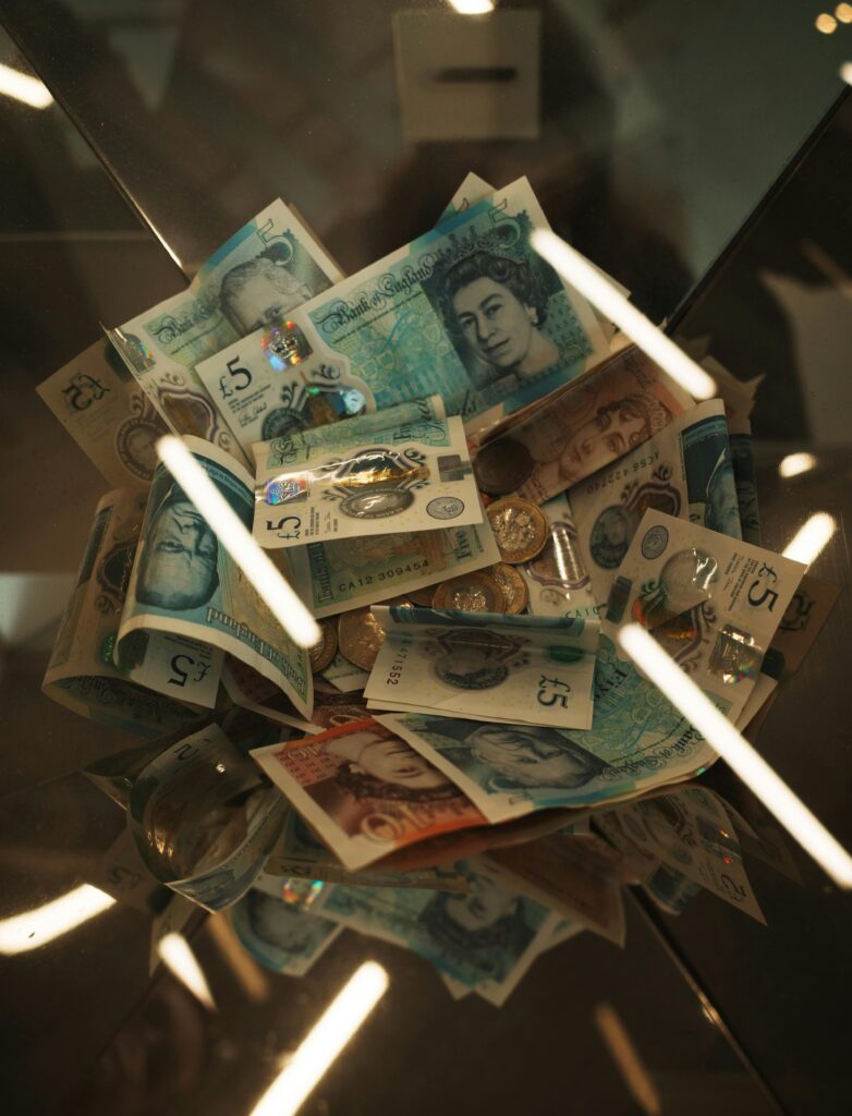 A collection of British pound notes and coins stacked inside a glass container.
